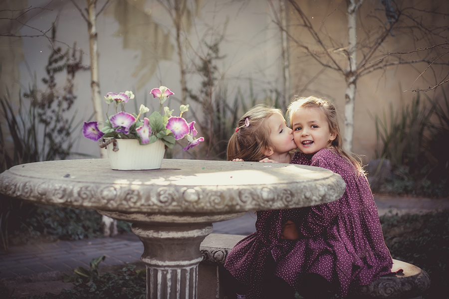 little sister giving her big sister a kiss